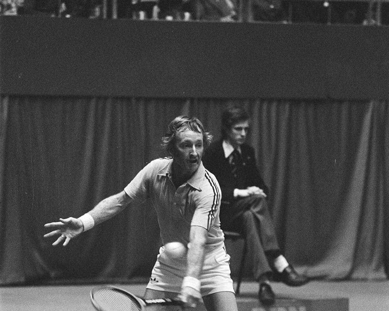 Rod Laver stretching for a forehand on an indoor court in the 1970s