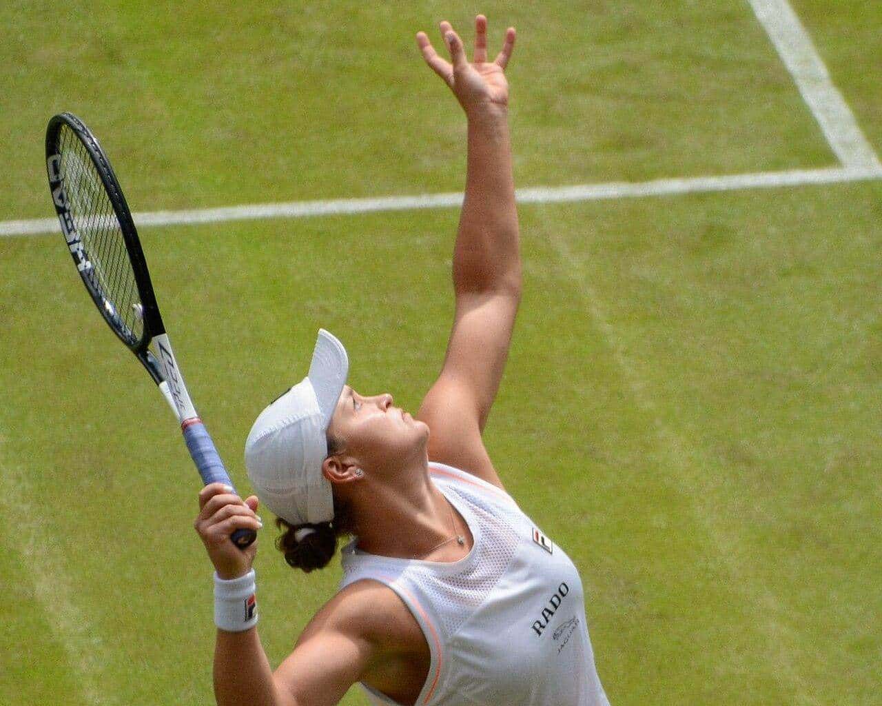 Ash Barty tossing the ball to serve on a grass court at Wimbledon in 2019