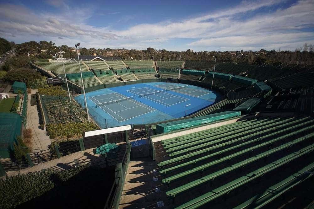 The centre court and green grandstand seating at Kooyong Stadium under a blue sky