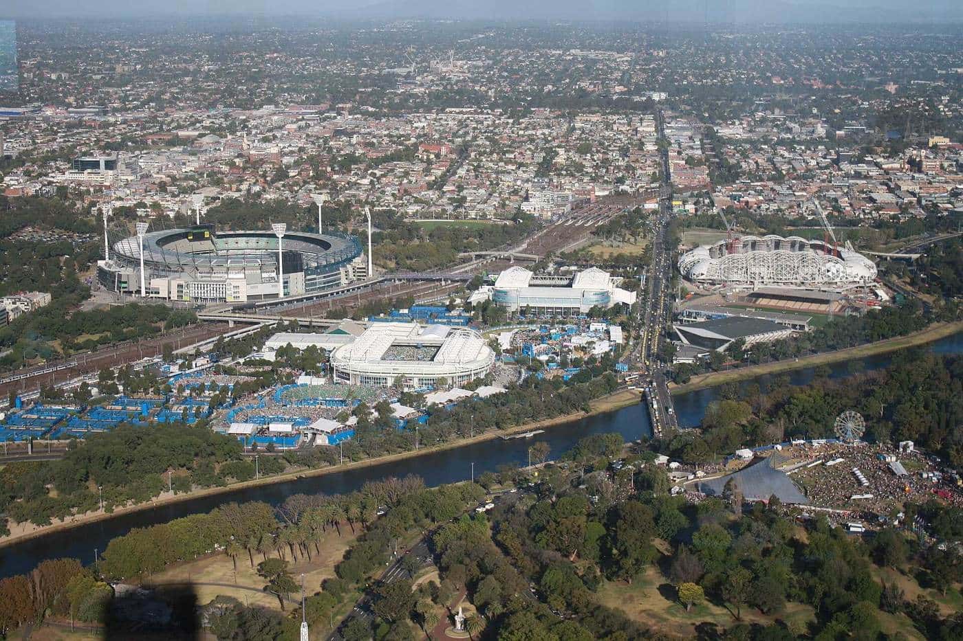 An aerial view of the Melbourne sports precinct with tennis arenas and courts beside the Yarra River